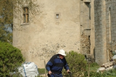 Un des moines passe le motoculteur dans le jardin de l'abbaye. La tour de l'abbé est visible en arrière-plan.