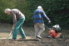 Aidé d'un bénévole, l'un des moines passe le motoculteur dans le jardin de l'abbaye.