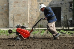 Un des moines passe le motoculteur dans le jardin de l'abbaye.